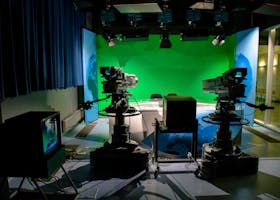 A TV studio setup featuring cameras and a green screen for production purposes.
